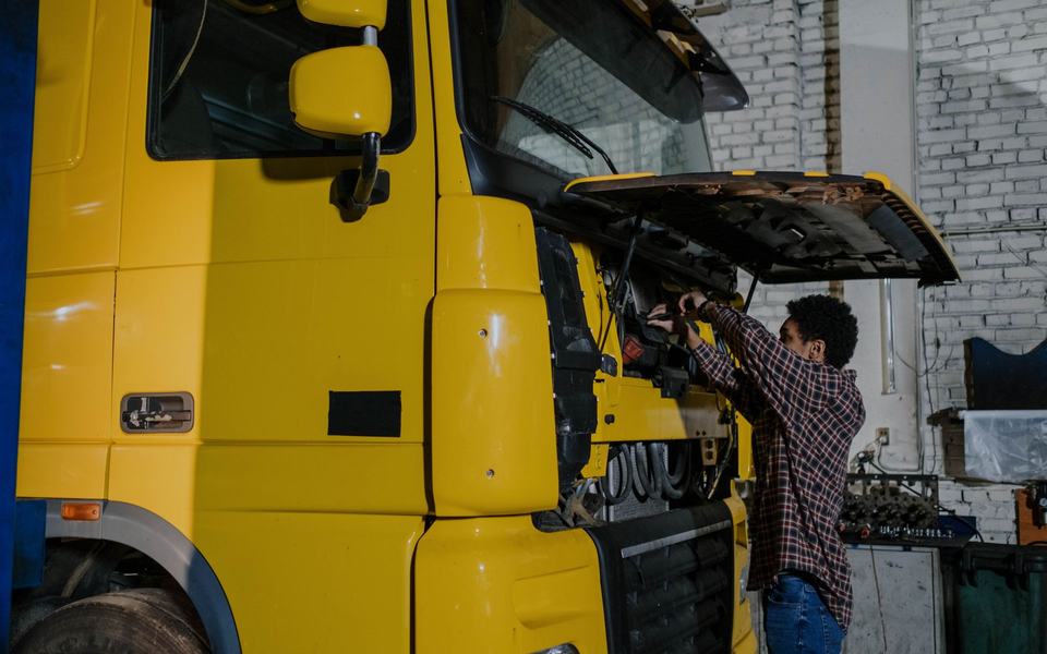 Mecânico trabalhando na cabine aberta de um caminhão amarelo